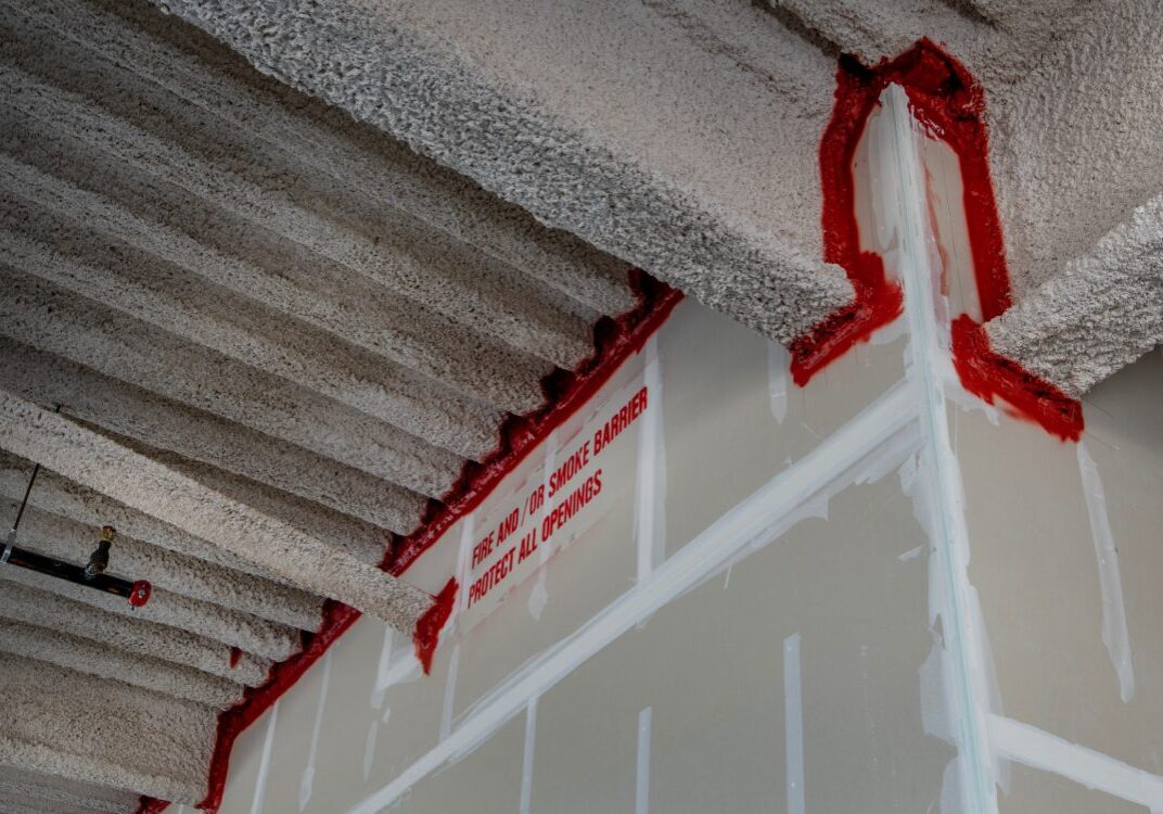 Ceiling with fireproofing material and red sealant.